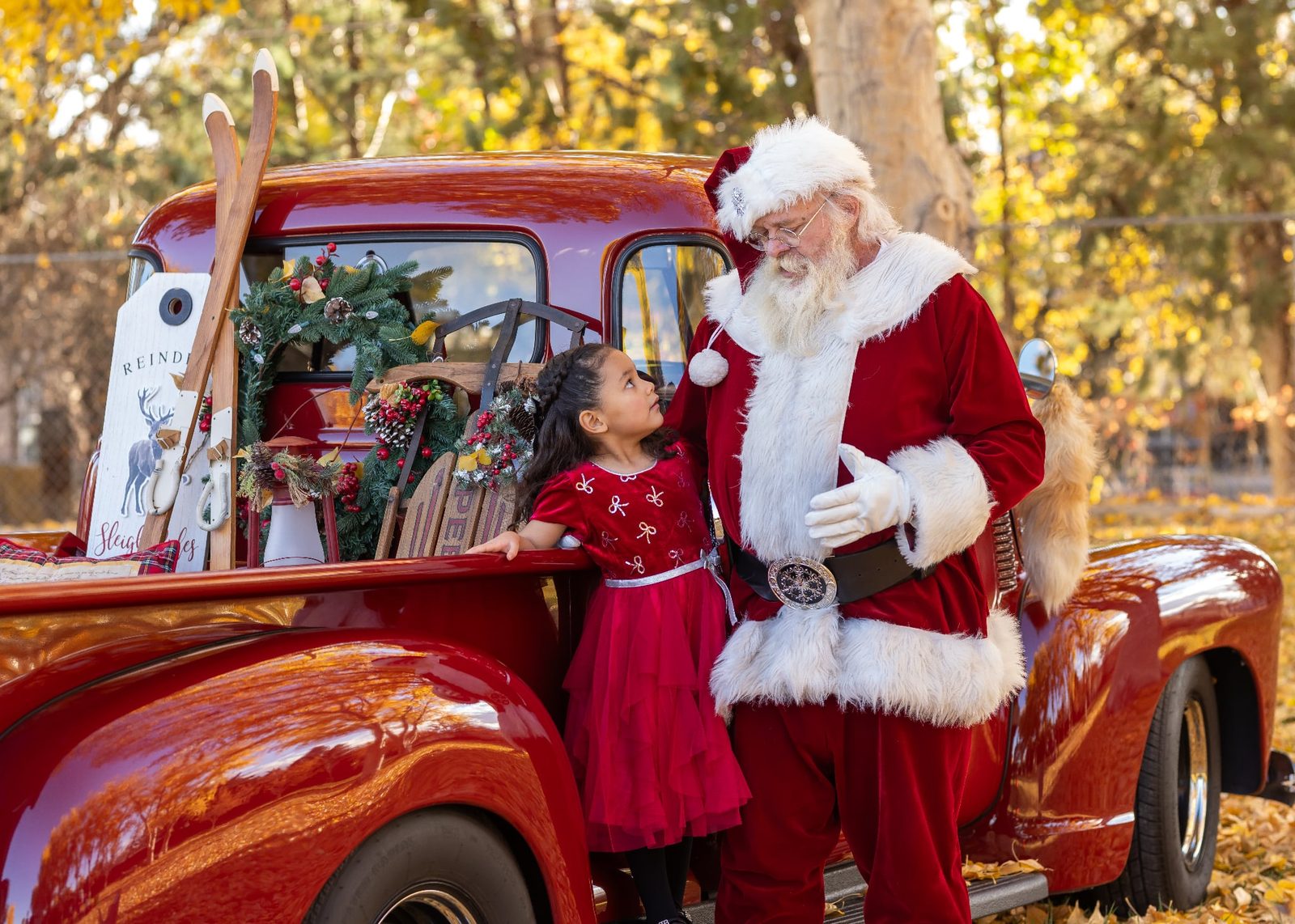 A girl looks up at Santa Michael beside a red truck